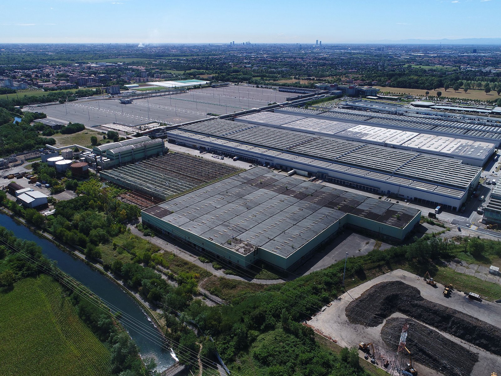 Vista aerea obliqua: edifici, viabilità e corso d'acqua nello stesso quadro Vista aerea obliqua di un grande insediamento industriale con coperture, viabilità interna e un corso d'acqua
